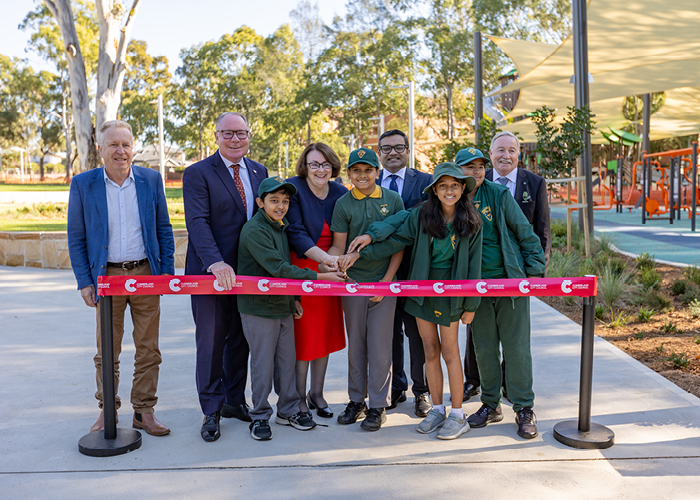 Councillors and local school children cutting a red ribbon at the reopening of Civic Park in Pendle Hill