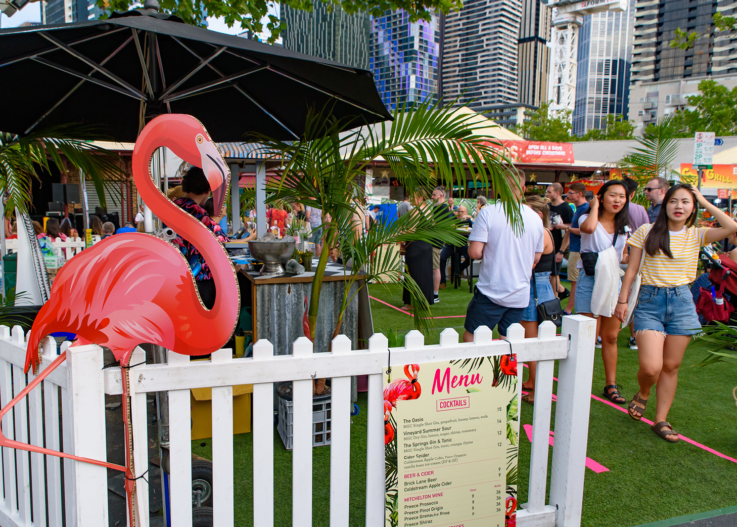 Group of young adults walking up to a street stall with a flamingo at the entrance