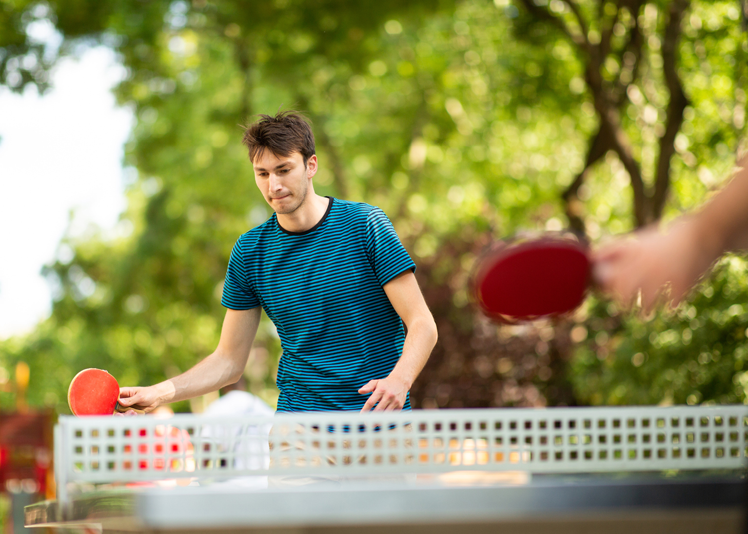 Young man playing a game of outdoor table tennis